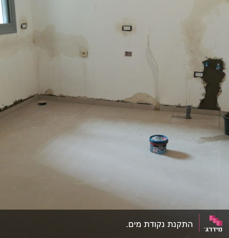 חדר עם קירות חשופים, דלי וצינור על הרצפה